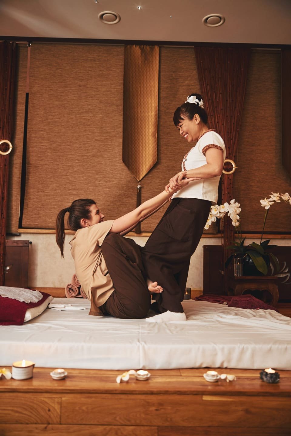 Therapist helping a smiling client up from the massage mat